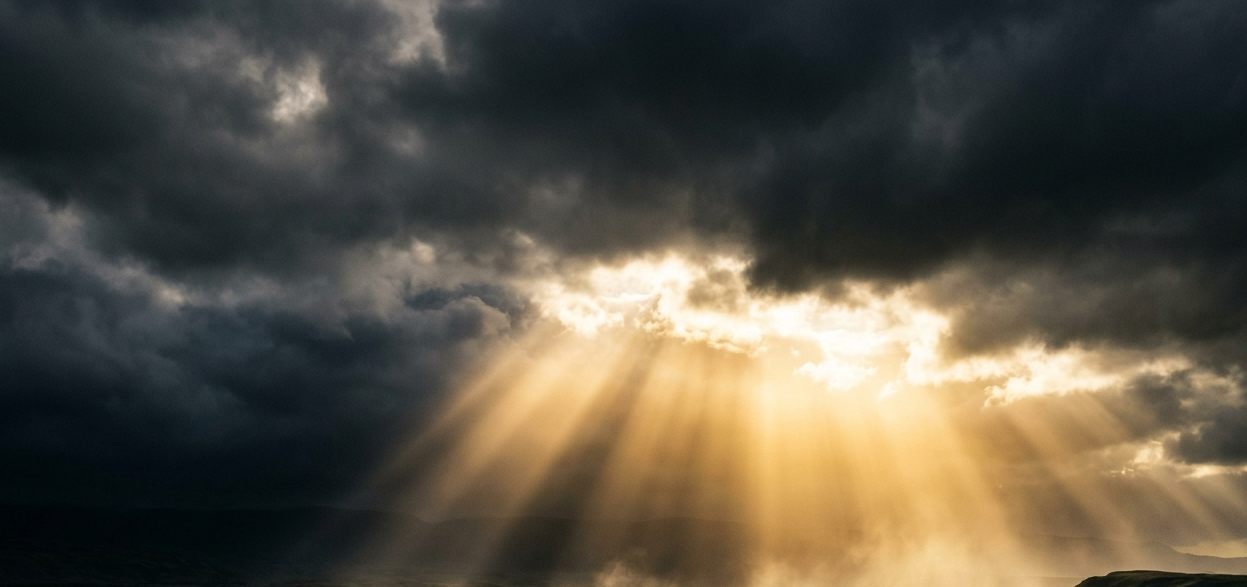 Rays of golden light breaking through darkness, symbolizing healing